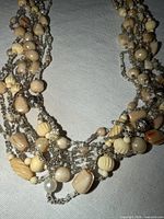 Full view showing multi-strand cream, white, beige and silver beaded necklace