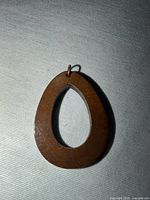 Front view of wooden teardrop pendant on fabric background