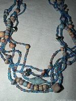 Close-up of intertwined blue seed beads with tan and blue stone beads and clasp visible