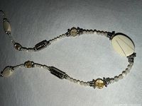 Close-up of necklace section showing faux pearls, cream oval bead, silver-tone spacer