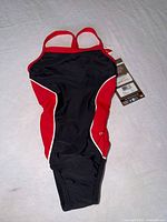Front view of red and black Dolphin girls swimsuit with tags attached