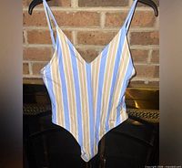 Front view of striped one-piece swimsuit on hanger