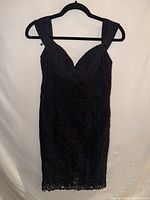 Full front view of black lace dress on hanger