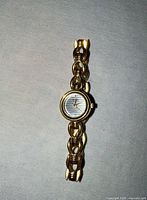 Front view of gold-tone watch with striped dial and link bracelet