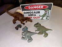 Group view of sign, plush dinosaur, two figures, vehicle