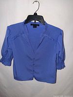 Front view of blue blouse on hanger showing overall style and sleeve length