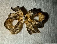 Front view of gold-tone bow brooch with rhinestones