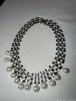 Full view of silver-tone link necklace with dangling faux pearls
