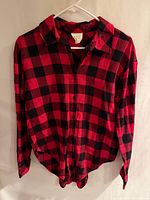 Front view of red and black plaid button-down shirt on hanger