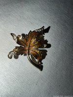 Front view of faux gold enamel leaf brooch with rhinestones