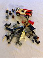 Overview of loose LEGO bricks and partially built pickup truck with minifigures