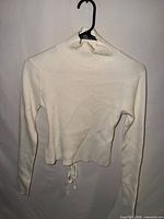 Front view of white ribbed long sleeve mock turtleneck top on hanger
