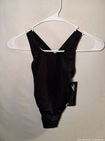 Front view of black Speedo one-piece swimsuit on hanger with tag visible