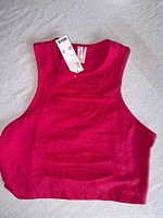 Full view of fuchsia crop tank displaying cutout design and tags
