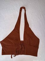 Full view of rust brown halter crop top laid flat