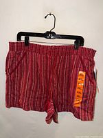 Front view of burgundy striped shorts on hanger showing waistband and tags