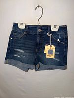 Front view of dark denim rolled cuff shorts with hang tag visible