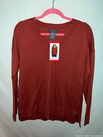 Front view of burnt orange V-neck sweater on hanger