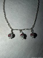 Full view of silver-tone necklace showing three ceramic floral charms