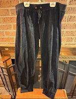 Full view front of black velour sweatpants hanging