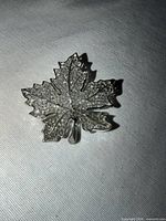 Front view of silvertone filigree maple leaf brooch
