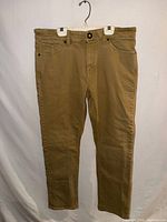 Full front view of tan Volcom jeans hanging