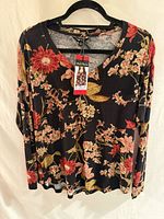 Front view of black floral long-sleeve shirt on hanger