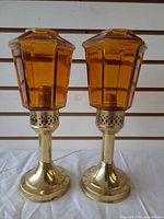Front view of both brass candlestick lamps with amber glass shades