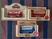 Front view of three boxed Lledo buses showing colours, box fronts, graphics