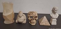 Group shot of vase, Buddha figurine, skull head, pyramid, bust