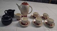 Full set showing coffee pot, five cups with saucers, matching creamer, black creamer and lidded sugar bowl