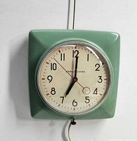 Front view of green square General Electric wall clock showing dial and hands