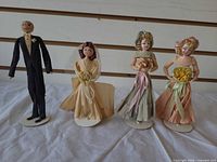 Front view of all four vintage crepe-paper wedding cake toppers