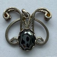 Front view of sterling pendant showing cabochon gemstone and scroll design