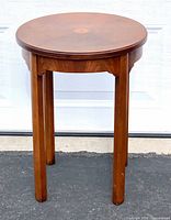 Full view of round wood end table on driveway