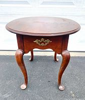 Full view of oval end table showing legs, drawer and hardware