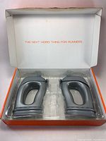 Open retail box showing two grey TU FLO handheld water bottles in plastic tray