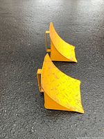 Top view of both yellow steel wheel chocks showing diamond-plate tread