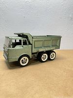 Left-front view of green Structo Deluxe Dumper toy truck showing cab, wheels, dump bed