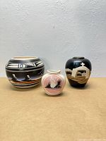 Front view of three pottery vases showing designs and relative sizes