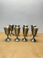 Front view of eight metal goblets standing in two rows