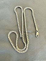 Full view of silver box chain laid flat showing link style and clasp