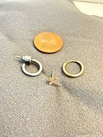 Front view of three single earrings beside a penny for scale