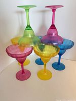Seven multicolour plastic margarita glasses grouped