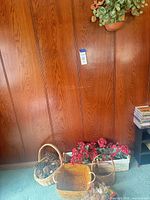 Overall view of baskets, pine cones, red faux flowers, and wall planter on wooden wall