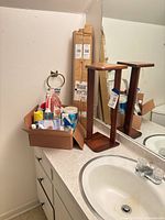 Overview of sink area with wooden shelf, boxed curtain rods and box of cleaners