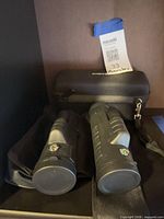 two binoculars with soft pouches and hard case visible