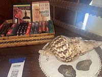 Overall lot with basket of cassettes, audiobooks, seashell, stones, teak rack in background