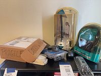 Shelf with packaged Logitech USB microphone, packaged Logitech H390 headset, loose mice, watch box, remote visible