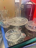 group view of all crystal items including cake stand, pitcher, vase, bowl, candlestick box, covered dish